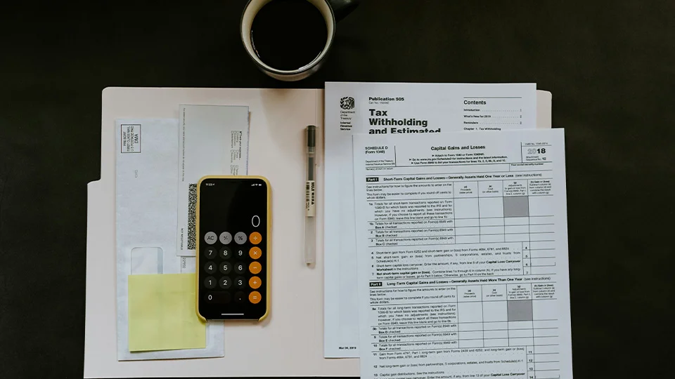 tax documents with calculator, pen, and other documents on a table