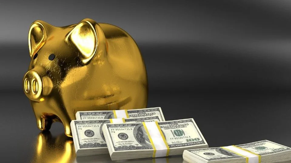 gold piggy bank with stacks of $100 bills banded together