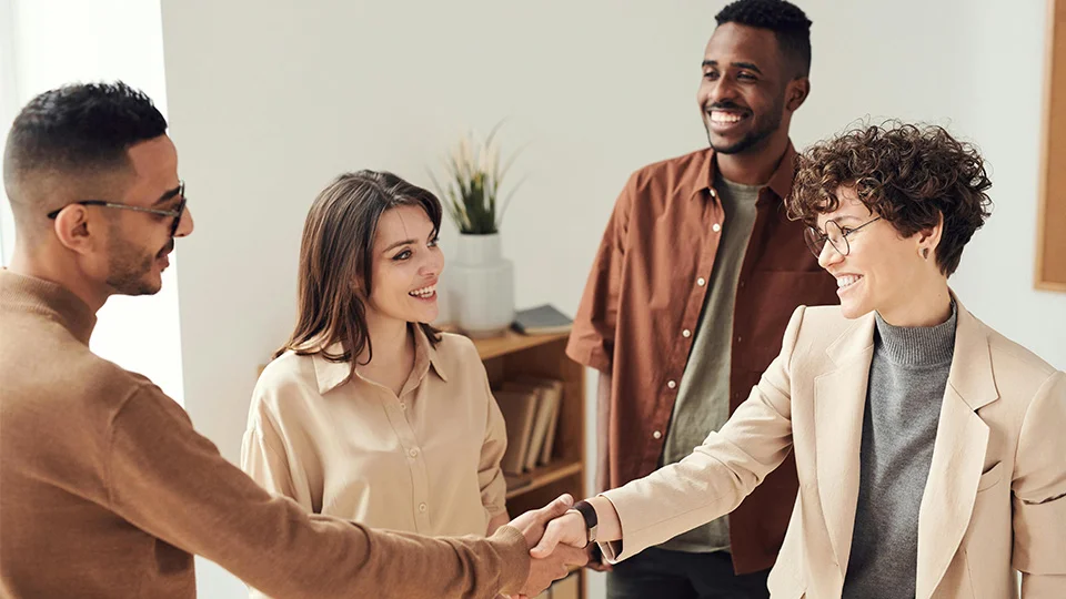 Group of people together in a room shaking hands