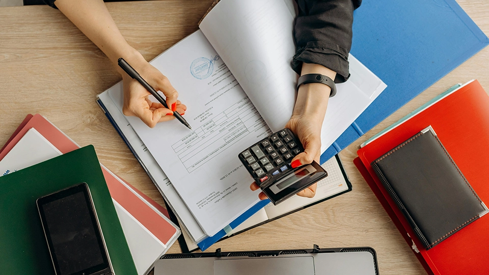 Personal using a calculator while filling out documents